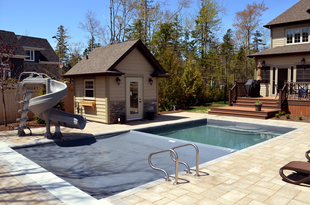 Foto de piscina actual de tamaño medio rectangular en patio trasero con adoquines de hormigón