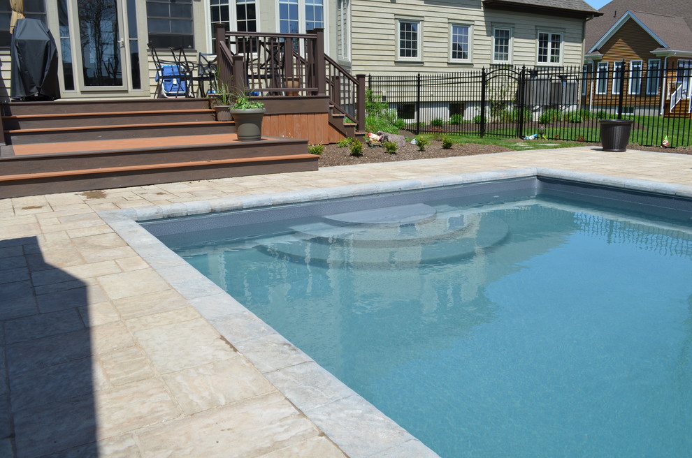 Réalisation d'une piscine arrière design de taille moyenne et rectangle avec des pavés en béton.