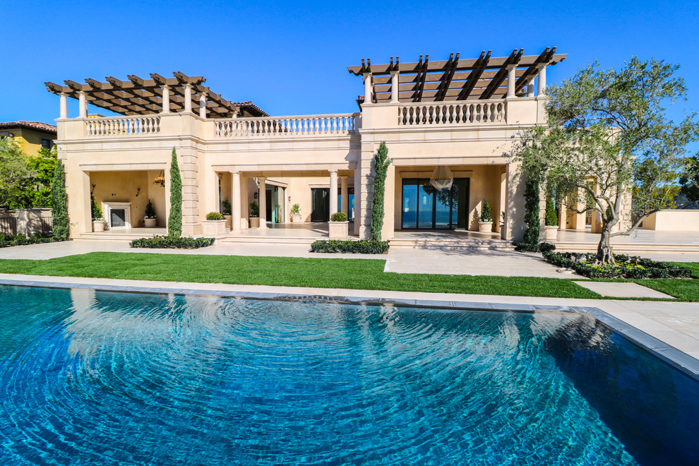 Diseño de piscina mediterránea grande rectangular en patio trasero con adoquines de hormigón