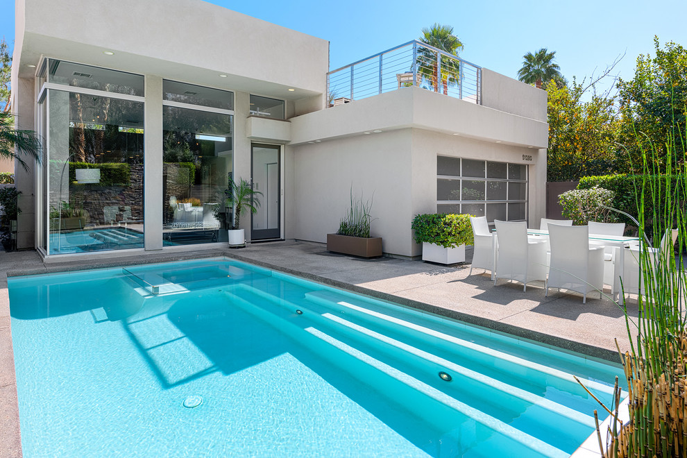 Foto di una piscina monocorsia moderna rettangolare di medie dimensioni e davanti casa con una vasca idromassaggio e lastre di cemento