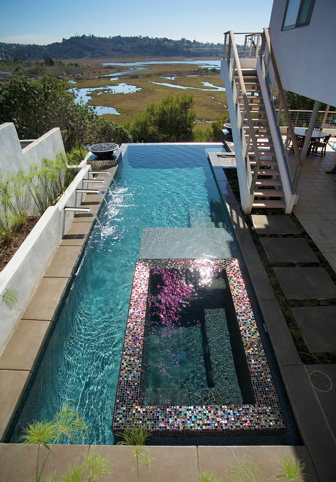 Diseño de piscina con fuente infinita actual grande en forma de L en patio trasero