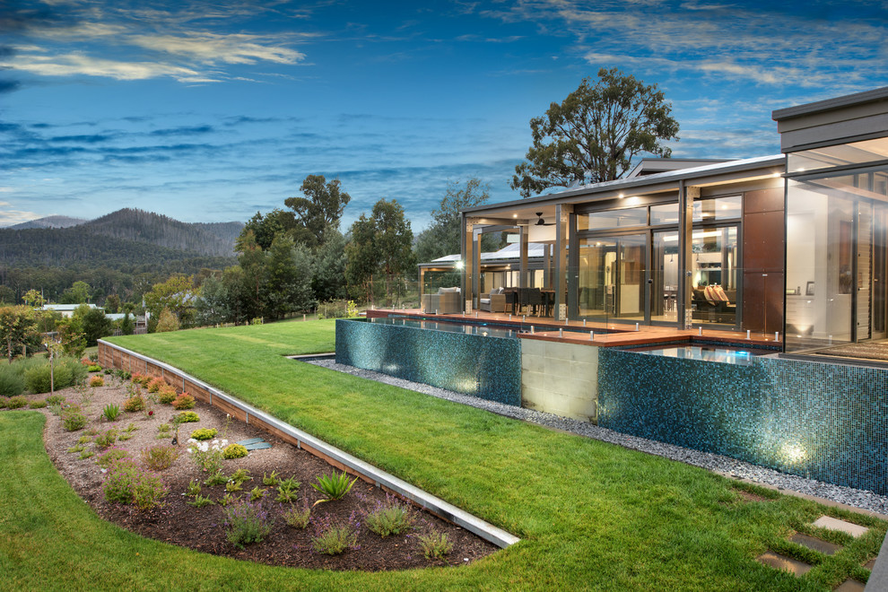 Diseño de piscinas y jacuzzis infinitos actuales de tamaño medio rectangulares en patio lateral con suelo de baldosas