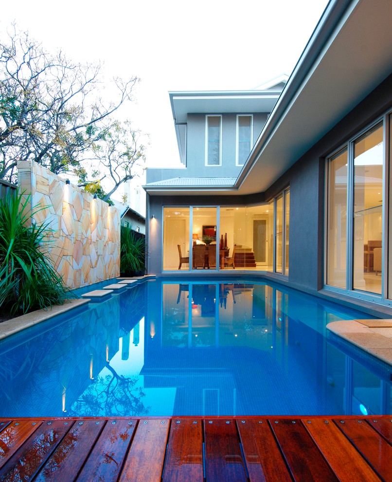 Стильный дизайн: спортивный, прямоугольный бассейн на заднем дворе в современном стиле с покрытием из каменной брусчатки - последний тренд