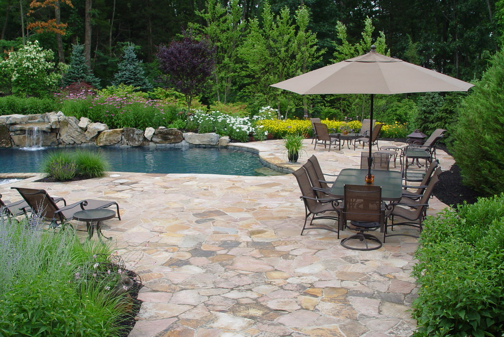 Inspiration for a medium sized mediterranean back custom shaped natural swimming pool in New York with a water feature and natural stone paving.