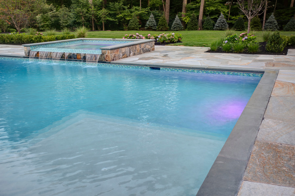 Modelo de piscinas y jacuzzis alargados de estilo de casa de campo de tamaño medio rectangulares en patio trasero con adoquines de piedra natural