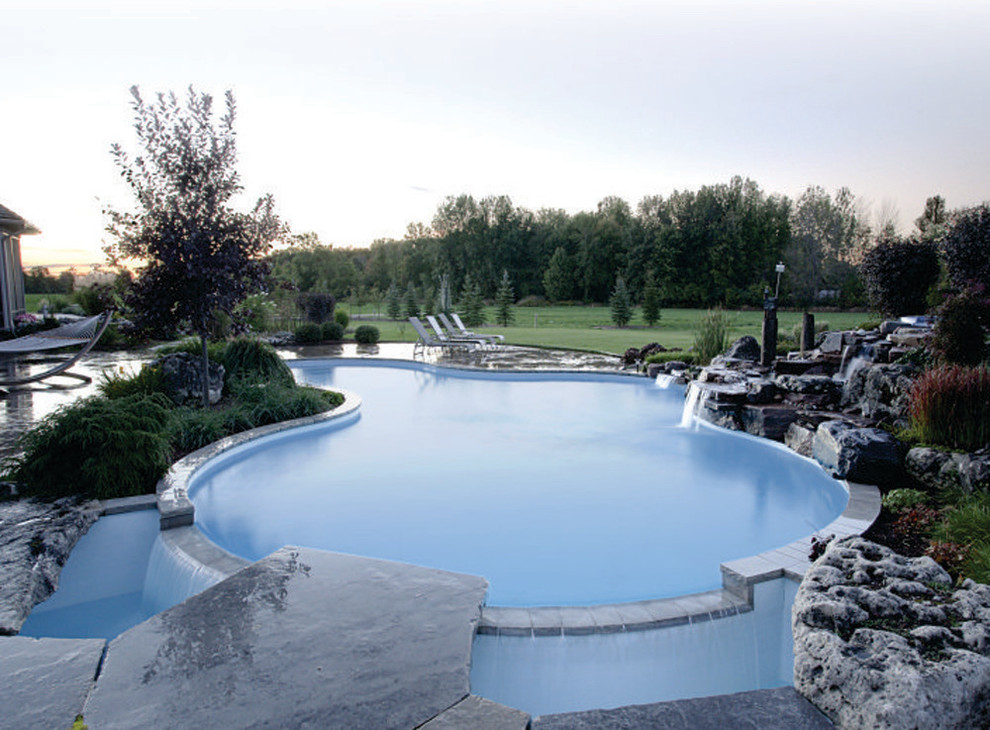 Idee per una grande piscina design personalizzata dietro casa con fontane e pavimentazioni in pietra naturale