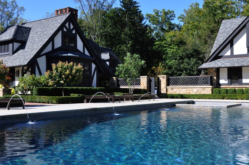 Idée de décoration pour une grande piscine arrière tradition rectangle avec un point d'eau et des pavés en pierre naturelle.
