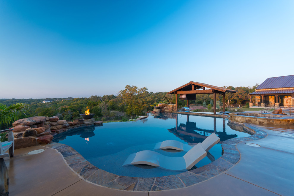 Ispirazione per una piscina a sfioro infinito stile rurale personalizzata dietro casa con una vasca idromassaggio