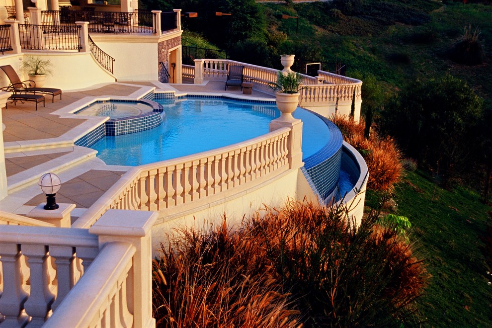 Large mediterranean back custom shaped infinity swimming pool in Los Angeles with a water feature and concrete paving.
