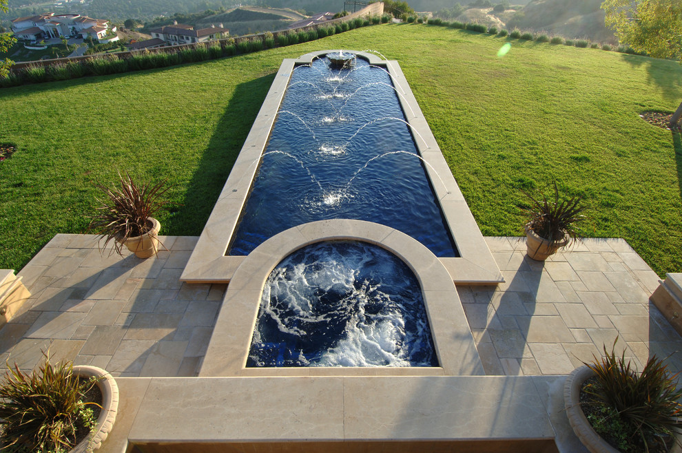 Immagine di una piscina naturale chic rettangolare di medie dimensioni e dietro casa con fontane e pavimentazioni in cemento