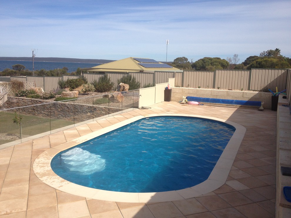 Foto di una piscina rotonda di medie dimensioni e dietro casa con pavimentazioni in pietra naturale
