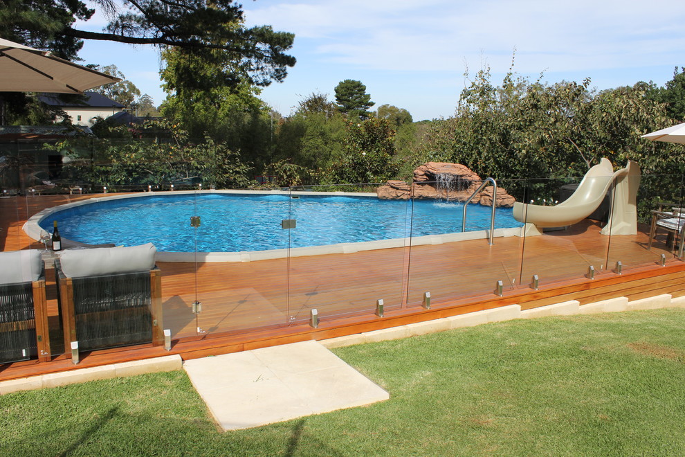 Medium sized back round swimming pool in Adelaide with a water slide and decking.