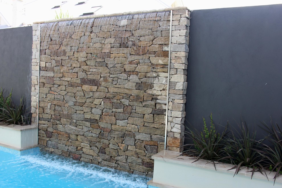 Idéer för att renovera en mellanstor funkis rektangulär pool på baksidan av huset, med en fontän