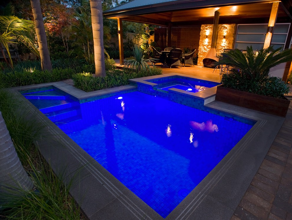 Пример оригинального дизайна: большой бассейн произвольной формы на заднем дворе в морском стиле с мощением тротуарной плиткой