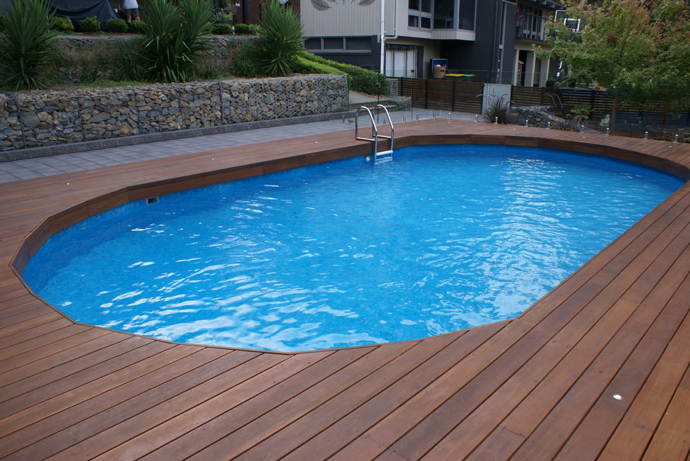 На фото: круглый бассейн среднего размера на заднем дворе в стиле модернизм с настилом с