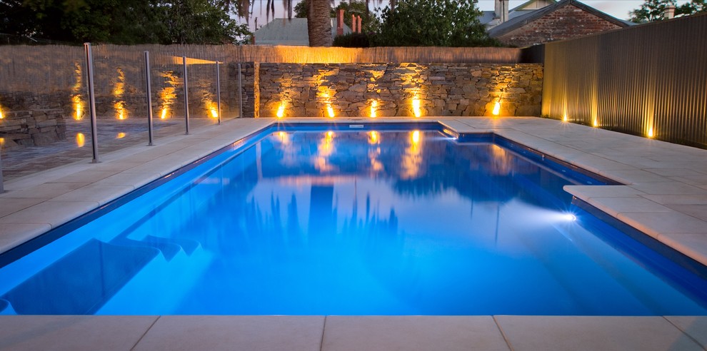 Diseño de piscina moderna de tamaño medio rectangular en patio trasero con adoquines de piedra natural