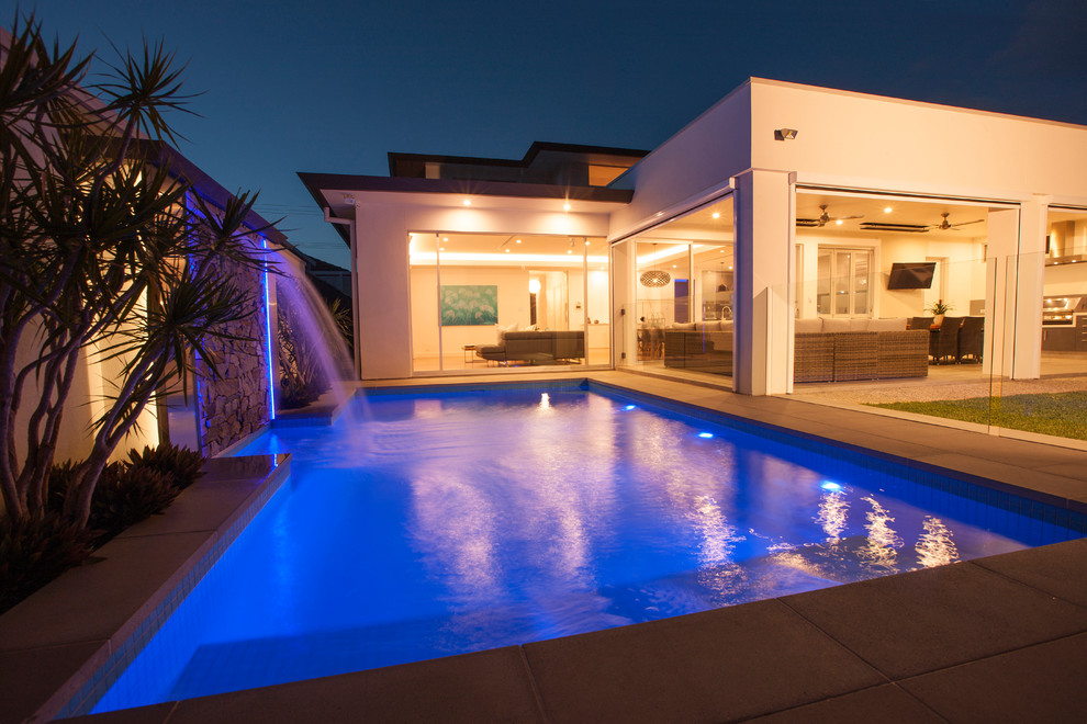 Foto på en stor funkis pool på baksidan av huset, med naturstensplattor