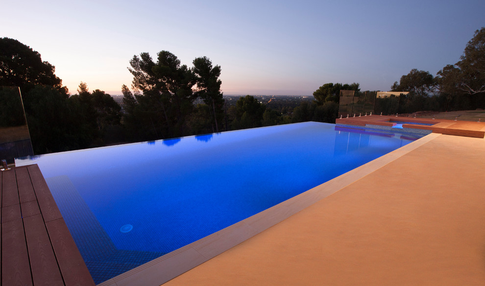 Imagen de piscina infinita minimalista grande rectangular en patio trasero con entablado