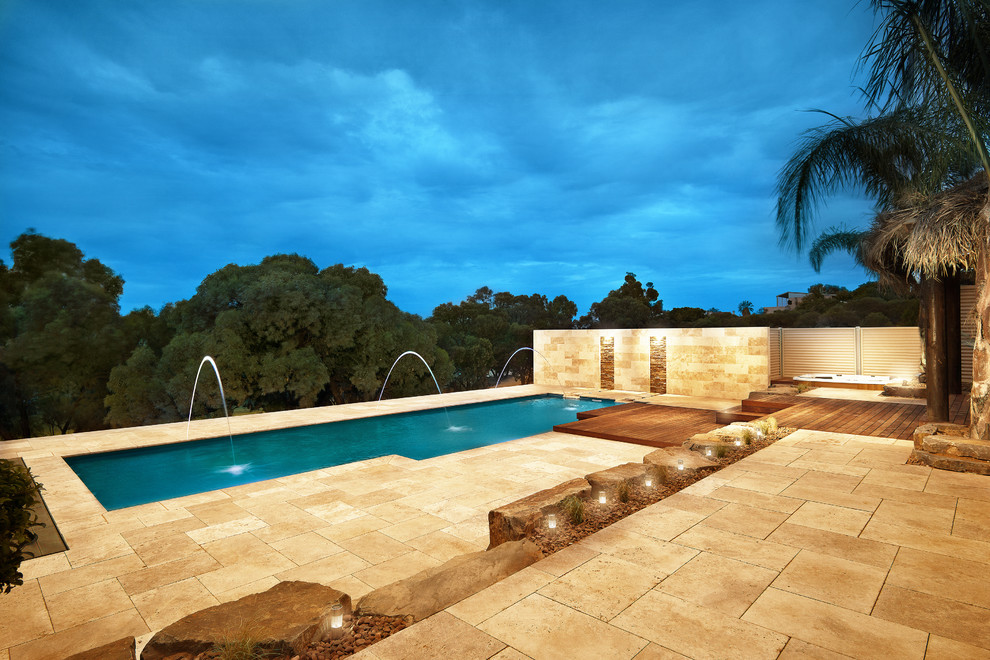 Exemple d'une grande piscine arrière moderne rectangle avec un point d'eau et des pavés en pierre naturelle.