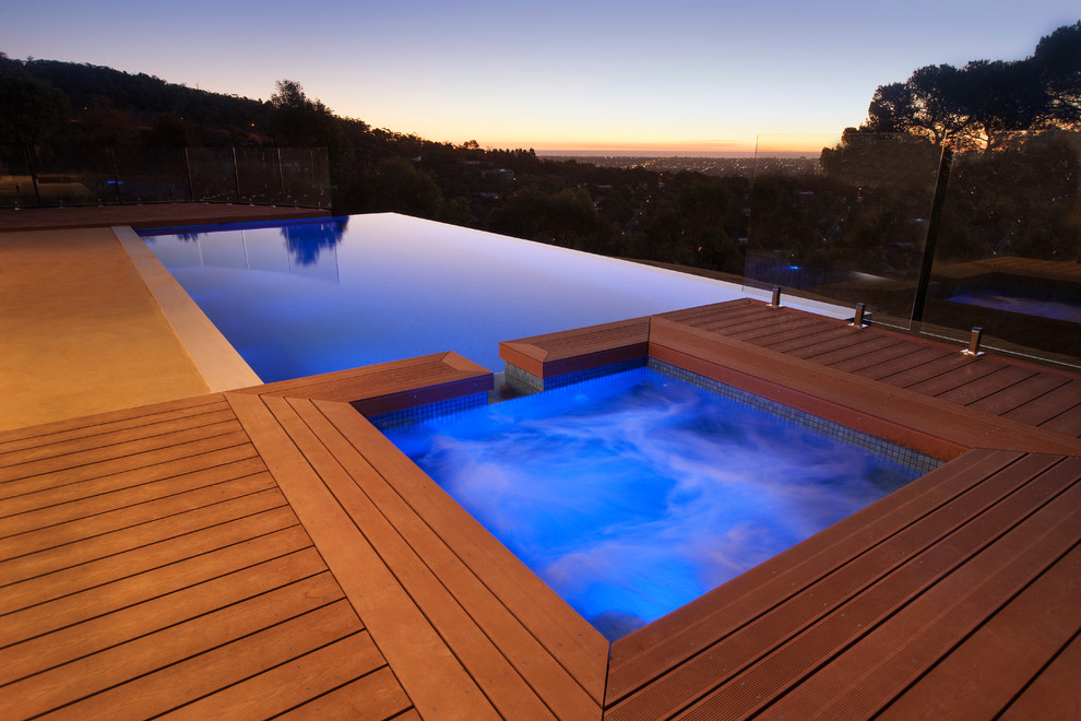 Idee per una grande piscina a sfioro infinito moderna rettangolare dietro casa con pedane