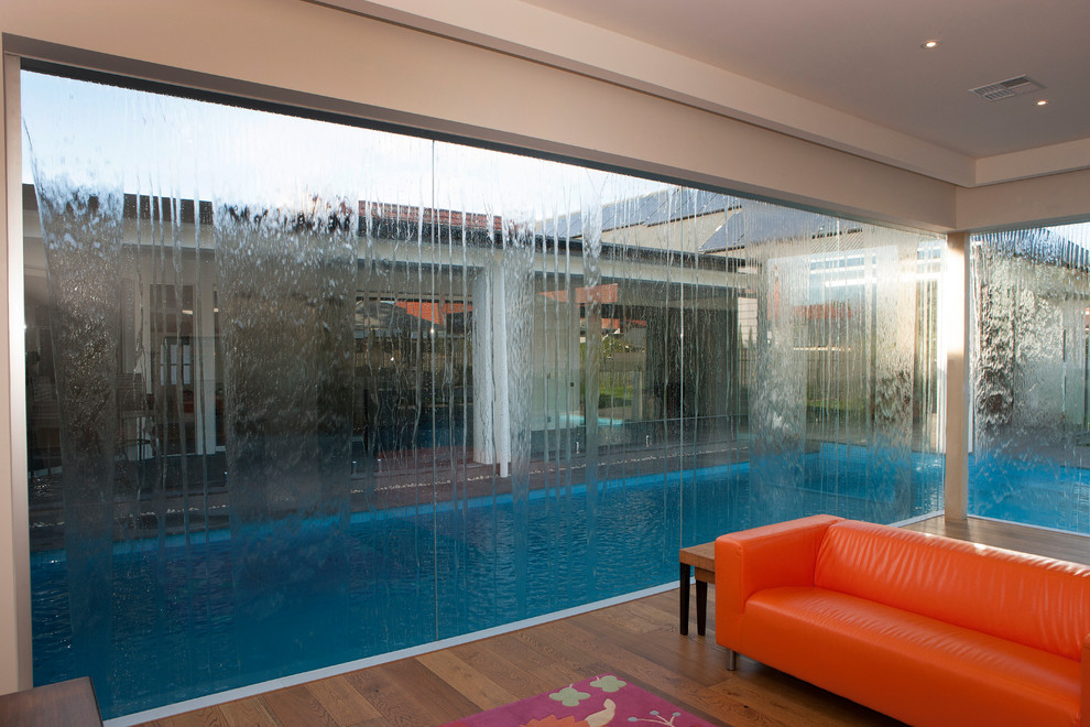 Diseño de piscina con fuente minimalista en forma de L en patio trasero con entablado