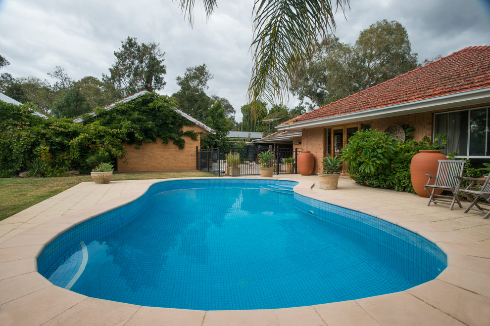 Design ideas for a large modern back kidney-shaped swimming pool in Adelaide with natural stone paving.