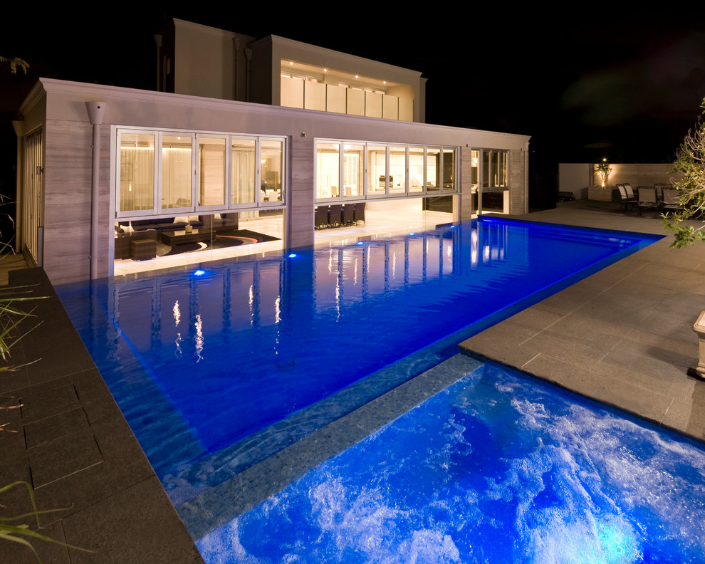Esempio di una grande piscina minimalista rettangolare dietro casa con pavimentazioni in cemento