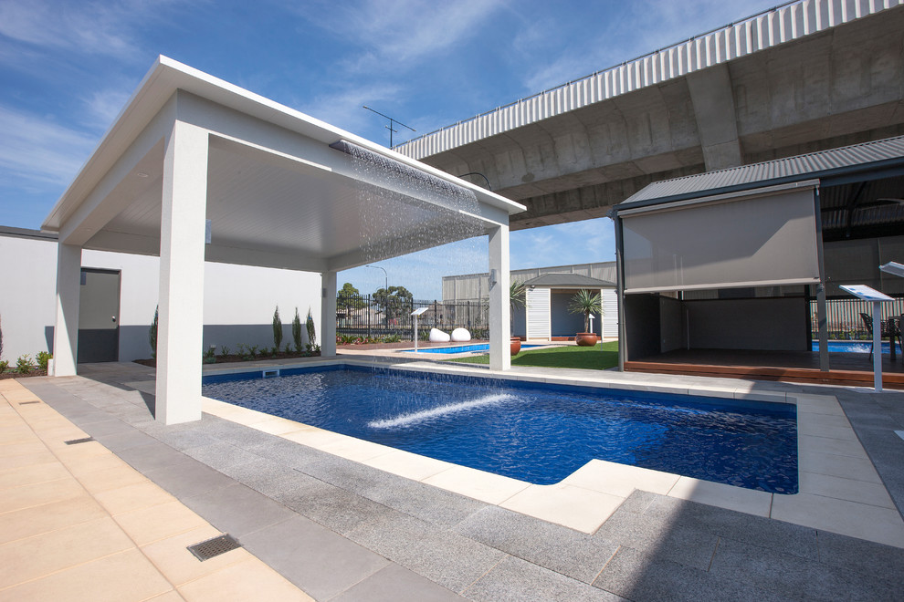 На фото: прямоугольный бассейн среднего размера в стиле модернизм с фонтаном и покрытием из каменной брусчатки