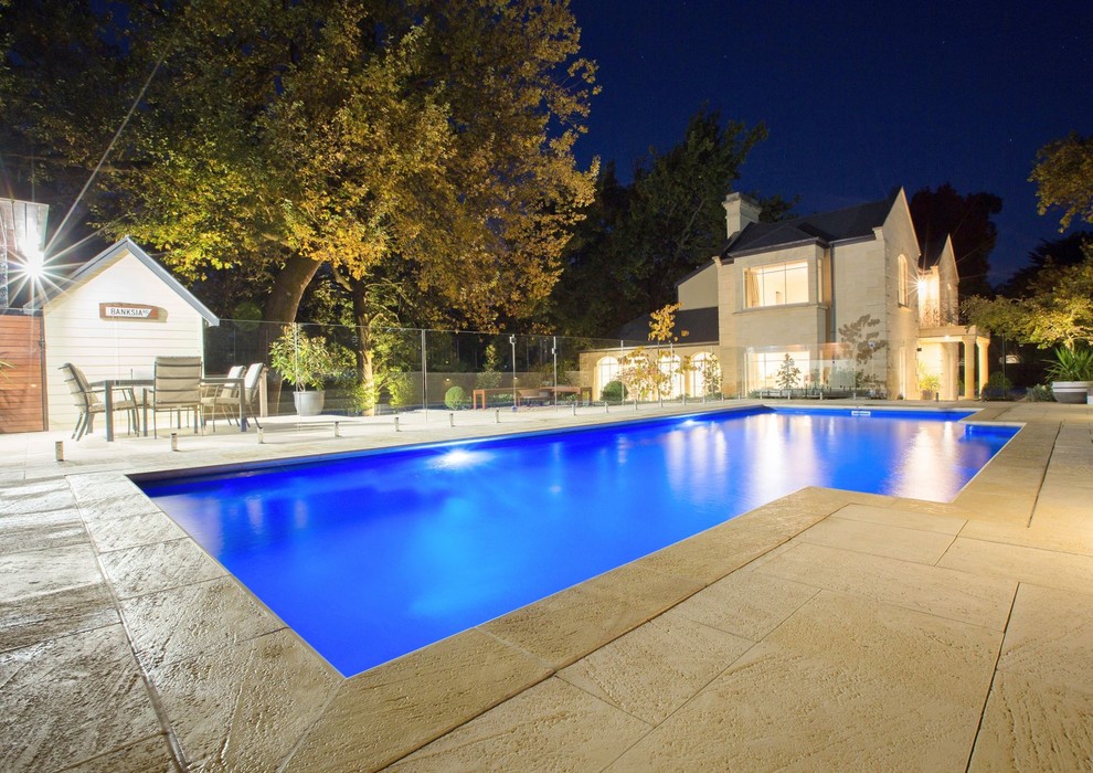 Ejemplo de piscina actual grande rectangular en patio trasero con adoquines de piedra natural