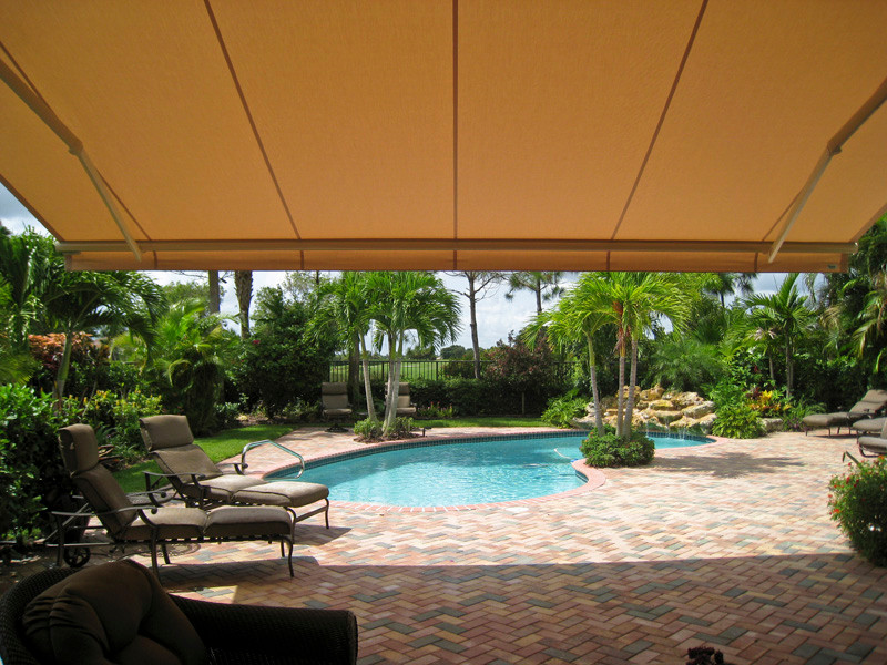 Immagine di una piscina monocorsia tropicale a "C" di medie dimensioni e dietro casa con fontane e pavimentazioni in mattoni