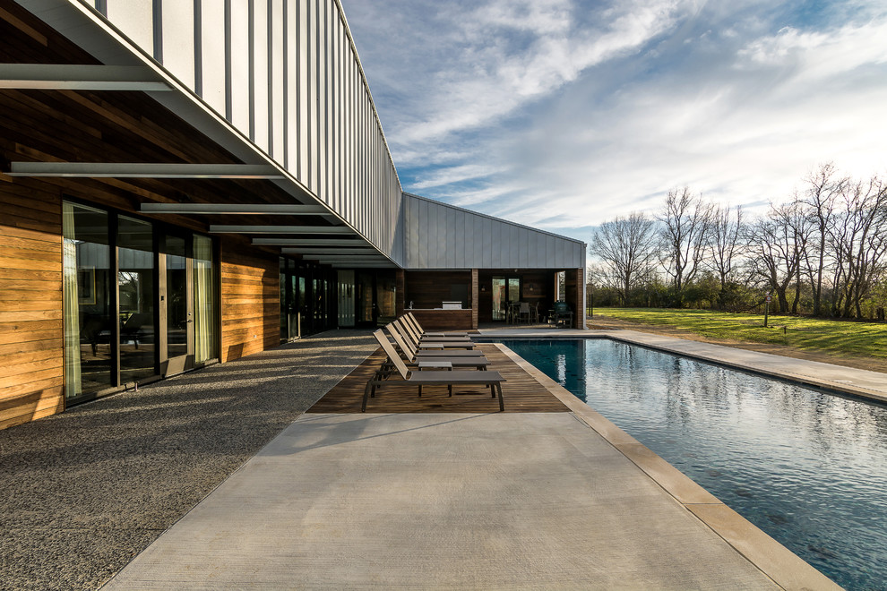 Moderner Pool hinter dem Haus in L-Form mit Betonplatten in Sonstige