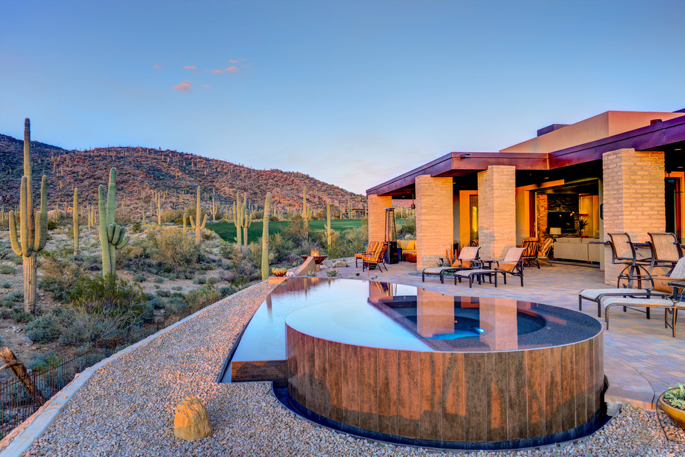 Immagine di una piscina a sfioro infinito design personalizzata dietro casa e di medie dimensioni con fontane e pavimentazioni in mattoni