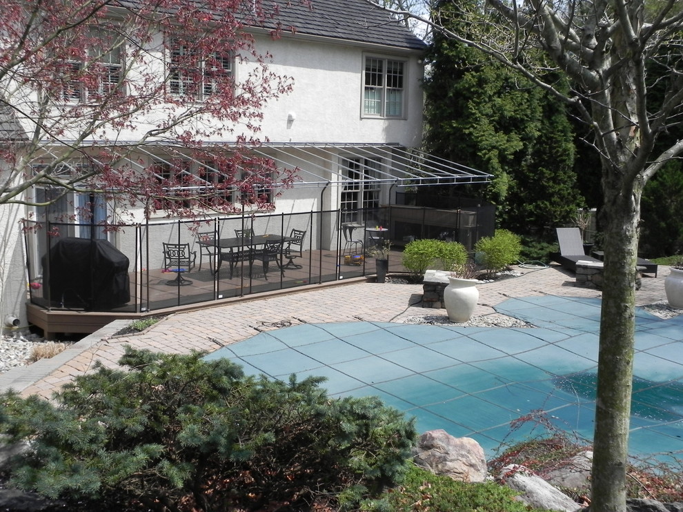 Ejemplo de piscina tradicional de tamaño medio en patio trasero con adoquines de ladrillo