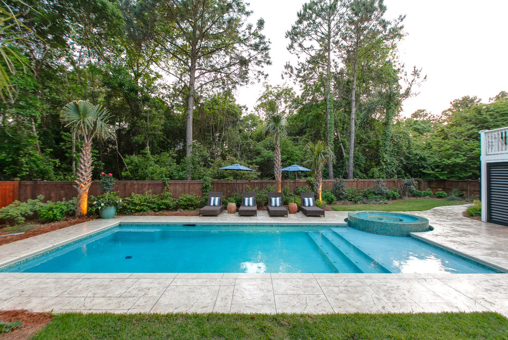 Modelo de piscinas y jacuzzis actuales grandes rectangulares en patio trasero con suelo de hormigón estampado