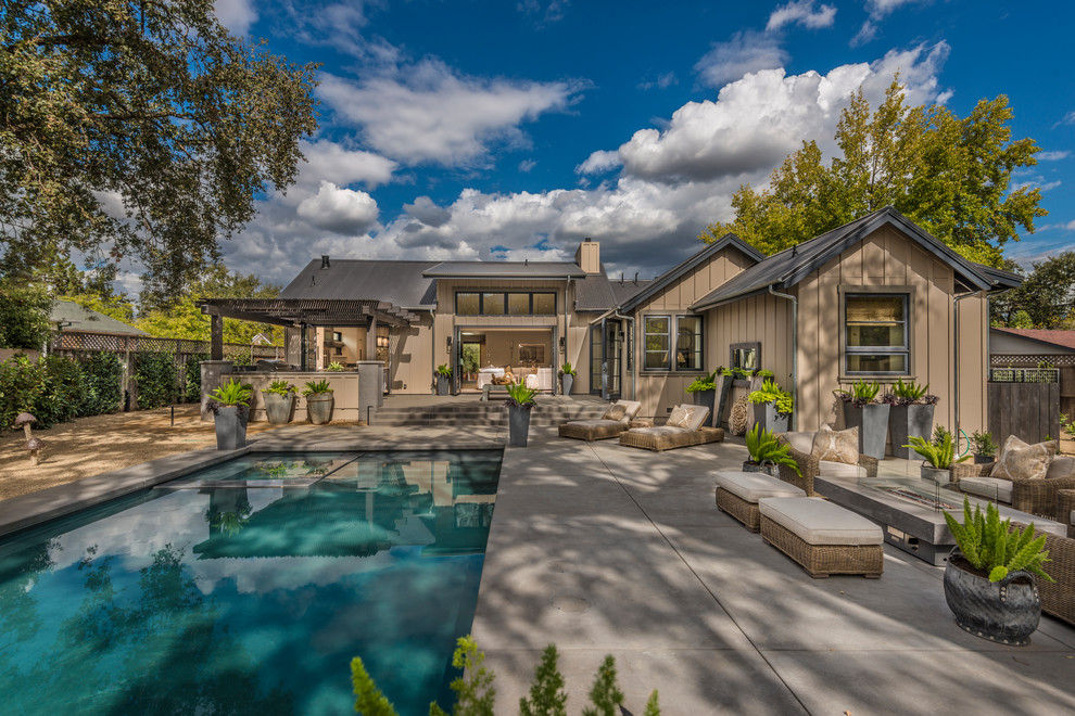 Diseño de piscinas y jacuzzis de estilo de casa de campo grandes rectangulares en patio trasero con losas de hormigón