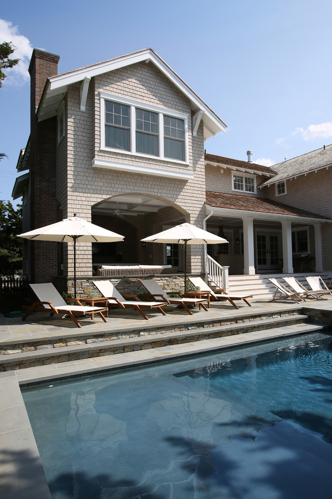 Modelo de piscina natural de estilo americano de tamaño medio rectangular en patio trasero con adoquines de ladrillo