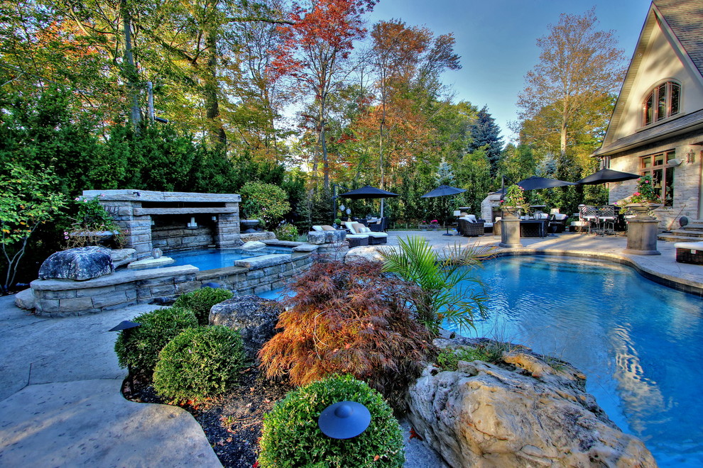 Foto de piscinas y jacuzzis naturales clásicos renovados grandes a medida en patio trasero con adoquines de piedra natural