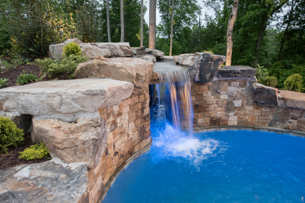 Ejemplo de piscina natural exótica extra grande a medida en patio trasero con paisajismo de piscina y adoquines de ladrillo