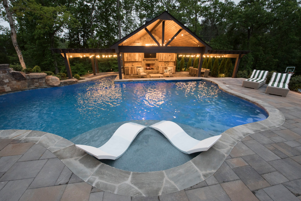 Diseño de piscina natural tropical extra grande a medida en patio trasero con paisajismo de piscina y adoquines de ladrillo
