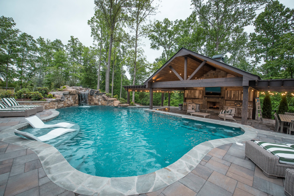 Modelo de piscina natural exótica extra grande a medida en patio trasero con paisajismo de piscina y adoquines de ladrillo
