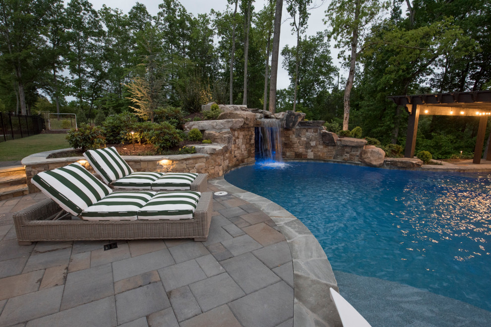 Ispirazione per un'ampia piscina naturale tropicale personalizzata dietro casa con paesaggistica bordo piscina e pavimentazioni in mattoni