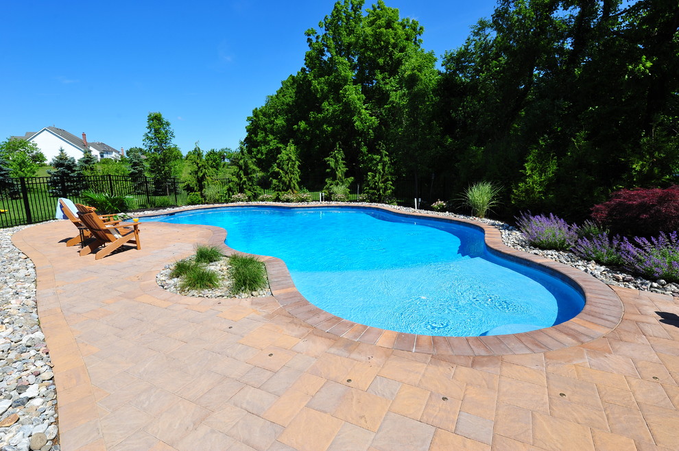 На фото: бассейн среднего размера, произвольной формы на заднем дворе в классическом стиле с фонтаном и мощением тротуарной плиткой с