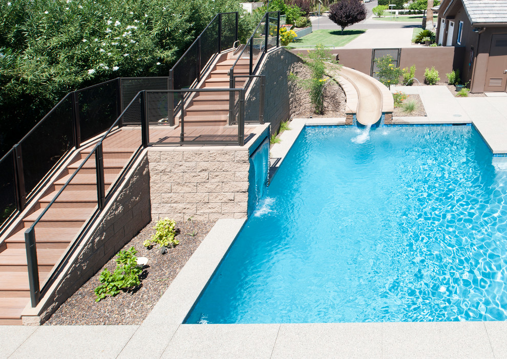 На фото: прямоугольный бассейн среднего размера на заднем дворе в современном стиле с водной горкой и мощением тротуарной плиткой с