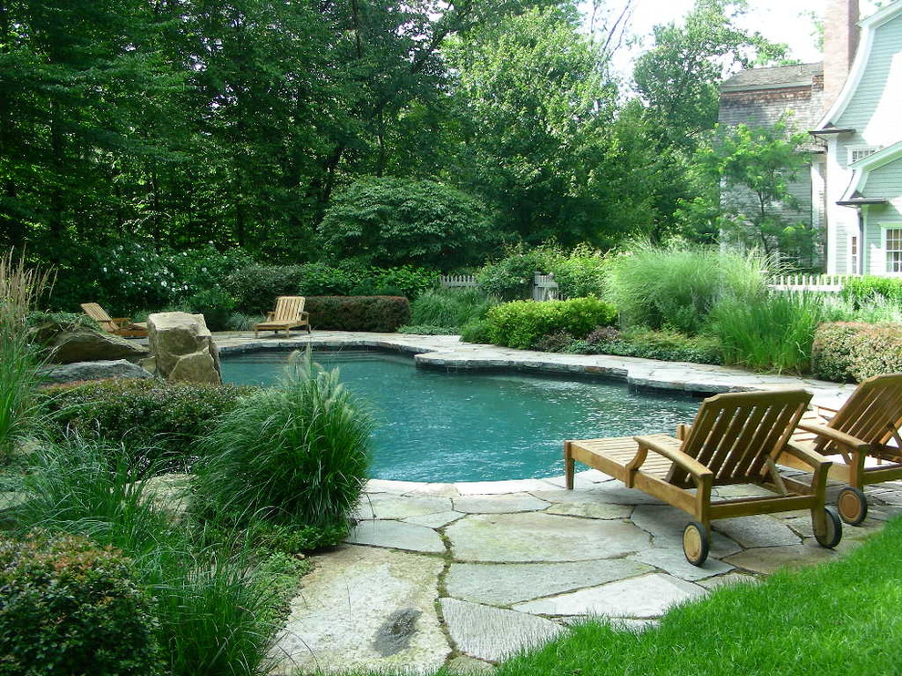 На фото: большой спортивный бассейн произвольной формы на заднем дворе в классическом стиле с джакузи и покрытием из каменной брусчатки