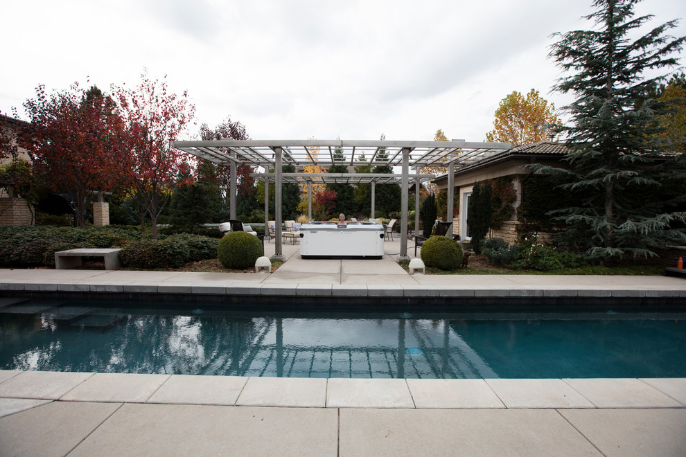 Idee per una grande piscina contemporanea rettangolare dietro casa con una vasca idromassaggio e lastre di cemento