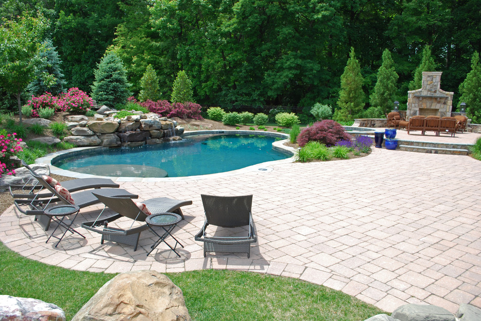 Foto de piscina con fuente clásica grande a medida en patio trasero con adoquines de hormigón