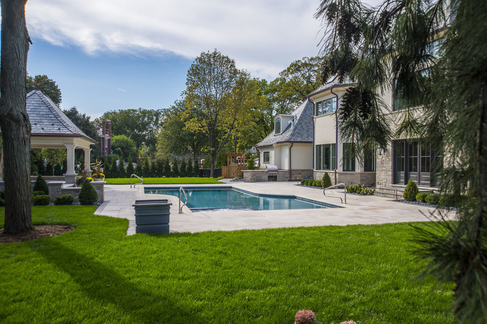 Foto de piscina de tamaño medio en patio trasero con adoquines de piedra natural
