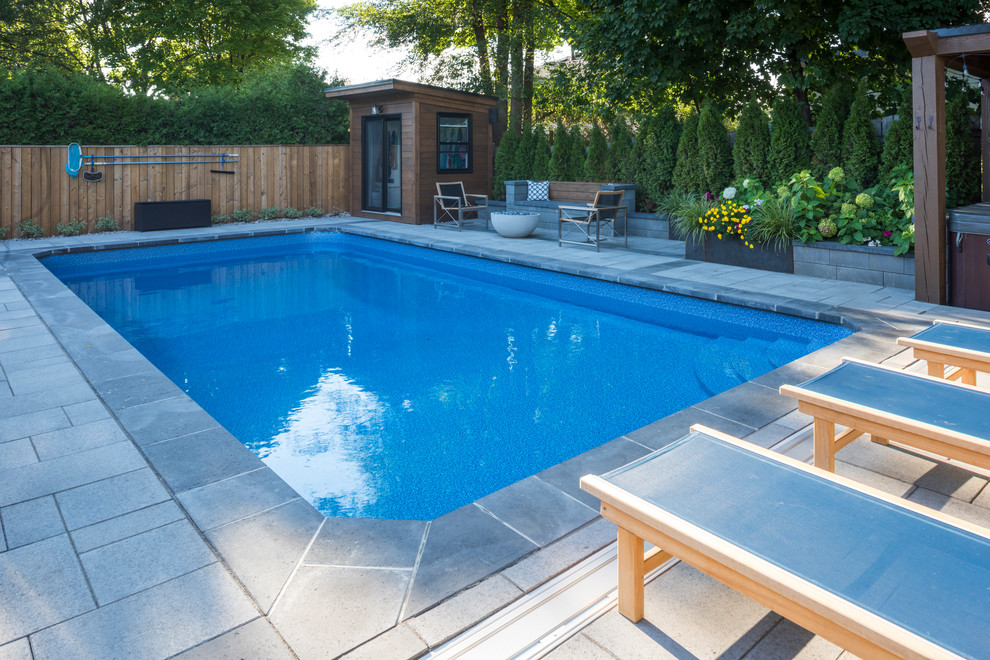 Foto de piscinas y jacuzzis alargados tradicionales grandes rectangulares en patio trasero con adoquines de hormigón