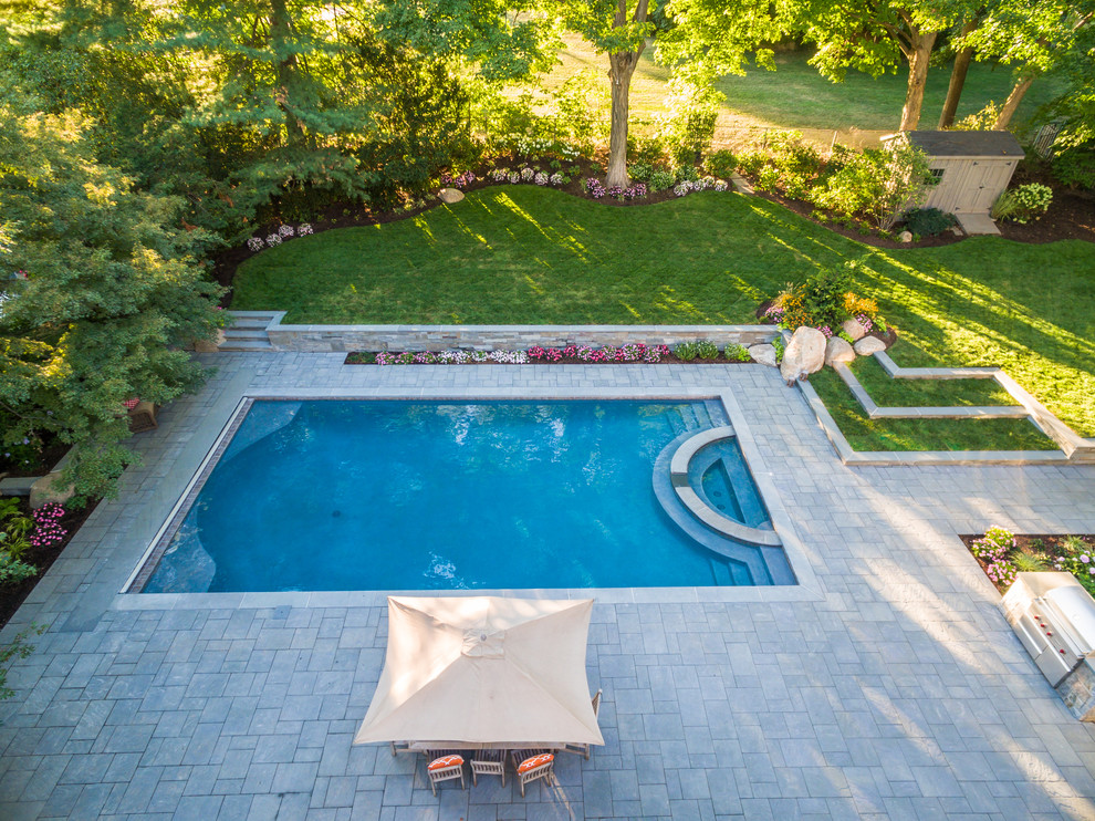 Стильный дизайн: большой естественный, прямоугольный бассейн на заднем дворе в стиле модернизм с джакузи и покрытием из каменной брусчатки - последний тренд