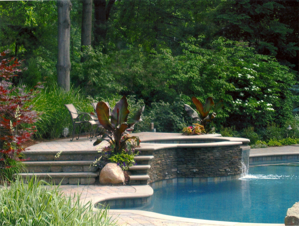 Foto på en mellanstor tropisk pool på baksidan av huset, med en fontän och marksten i betong